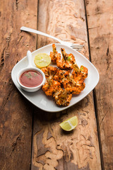 Tandoori Gobi / Roasted cauliflower Tikka is a dry dish made by roasting Cauliflowers in Oven/Tandoor. It's  popular starter food from India. served with ketchup. selective focus