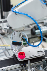 Focus on robotic arm's gripper. Industry 4.0 concept; artificial intelligence in smart factory. Robot picks up the product from automated car on the manufacturing line. Selective focus.
