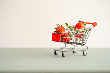Closeup strawberries in the shopping trolley. Cart carrying the strawberry with the isolated background