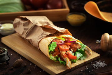Tasty mexican food burrito with vegetables, spicy salsa sauce and vegetables on dark wooden rustic background