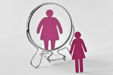 Slim paper woman looking in the mirror and seeing herself as a fat woman - Anorexia and eating disorders concept - 246771248