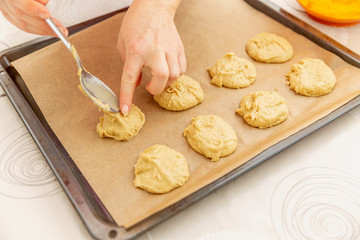 Woman lays out dough for cookies on baking tray in the kitchen, close-up