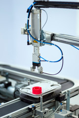 Industry 4.0 concept; artificial intelligence in manufacturing. Gripper picks up the product from automated car which is on the manufacturing line in a smart factory.