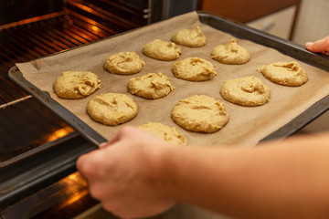 Woman lays out dough for cookies on baking tray in the kitchen, close-up