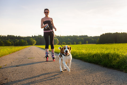 Girl skating with Beagle dog outdoors in nature.