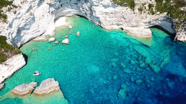 Aerial bird's eye view video taken by drone of caves  and boats docked in caribbean tropical beach with turquoise - sapphire waters and caves forming a blue lagoon