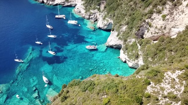 Aerial drone cinematic video of exotic paradise with boats anchored in Caribbean tropical bay with turquoise - sapphire waters and caves forming a blue lagoon