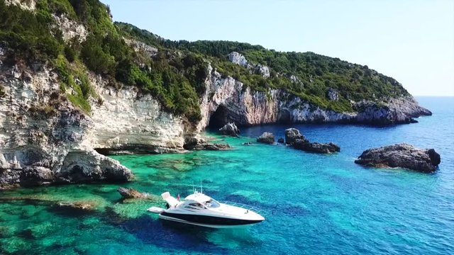 Aerial bird's eye view video taken by drone of caves  and boats docked in caribbean tropical beach with turquoise - sapphire waters and caves forming a blue lagoon
