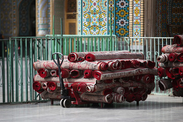wheelbarrow with bunch of red carpets in a mosque in Qom, Iran