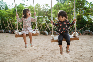 togetherness of the two sisters when playing a swing at the playground