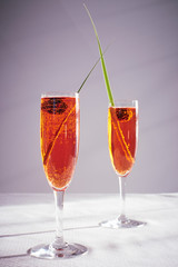 two spriz drinks with green leaf decoration in a flute crystal glass