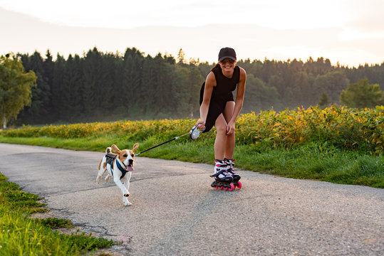 Girl skating with Beagle dog outdoors in nature.