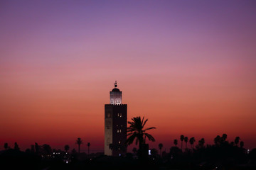 Beautiful sunset in Marrakech, Morocco. Silhouette of oriental architecture minaret tower in front of colorful purple creamy sky