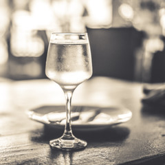 Glass of white wine on a table in a restaurant. Black and white