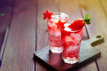 Sparkling pink strawberry lemonade on dark wooden background