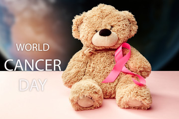 The text world cancer day and a pink ribbon with toy bear on a pink background. The cancer, health, breast, awareness, campaign, disease, help, care, support, hope, illness, survivor and healthcare