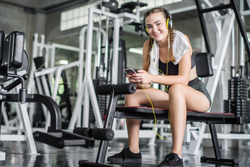 Fototapeta na wymiar young woman listening to music by smartphone in the gym
