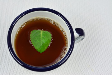 kubek herbaty z zielonym listkiem mięty 