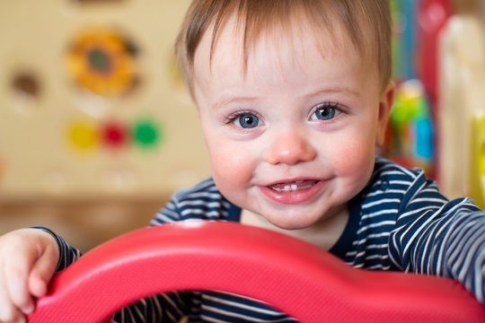 Portrait Of Cute Baby Boy Looking Out Of Play Pen And Smiling At Camera