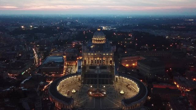 Aerial drone night video of Saint Peter's square, world's largest church - Papal Basilica of St. Peter's, Vatican - an elliptical esplanade created in the mid seventeenth century, Rome, Italy
