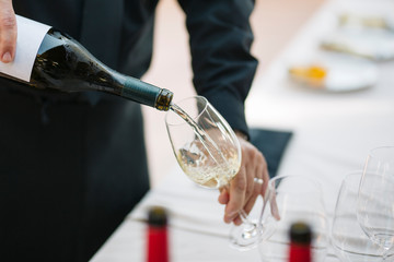 Unrecognizable waiter serving a glass of white wine