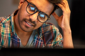 education, deadline and people concept - close up of creative man in glasses working at night office and thinking