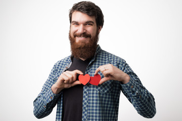 Smiling happy bearded man holding two red hearts standing over white background