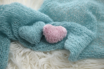 Fototapeta na wymiar Pink and blue hand knit hearts on blue knit shawl