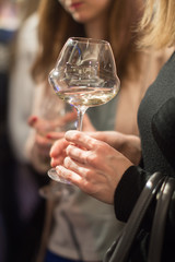 Woman holding a glass of white wine at a presentation