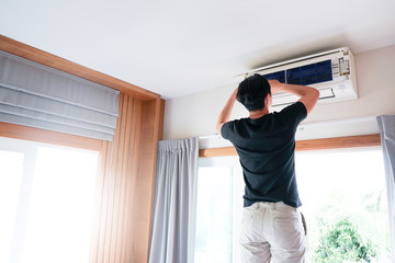Technician man repairing ,cleaning and maintenance Air conditioner on the wall in bedroom.On site home service,Business ,Industrial concept.