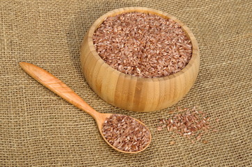 Uzbek devzira, the red rice in a bamboo bowl and in wooden spoon on burlap