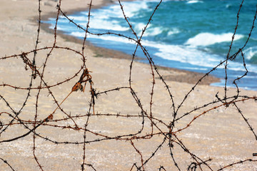 Old rusty barbed wire fence on a beach