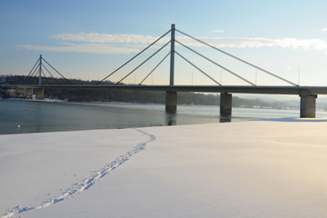 Fototapeta na wymiar Path in snow with bridge and river in background