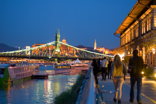 Waterfront promenade in Budapest by night, Liberty bridge, walking people