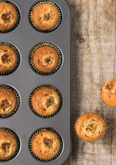 Homemade banana chocolate muffins in a baking form on a wooden background free space for text