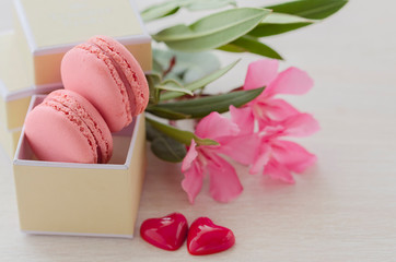 Pink Macaroons in gift box with  flower bouquet and two hearts. Love and Romantic present concept. Saint Valentine’s day celebration card.