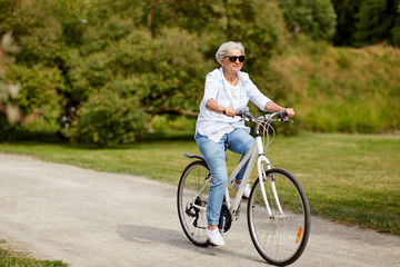 active old age, people and lifestyle concept - happy senior woman riding fixie bicycle at summer park