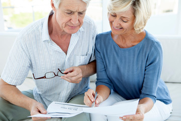 Senior couple doing home finance - fake bill - women smiling