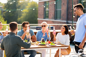 leisure and people concept - happy friends with non alcoholic drinks having barbecue party on rooftop