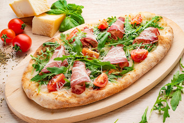 Pizza on Tabletop. Pizza wiht bacon, tomatoes, basil and arugula.