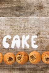 Inscription «Cake» of sugar on a wooden background. Fresh Homemade Chocolate Muffin Cake with...