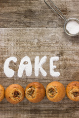 Inscription «Cake» of sugar on a wooden background. Fresh Homemade Chocolate Muffin Cake with blue background. free space for text