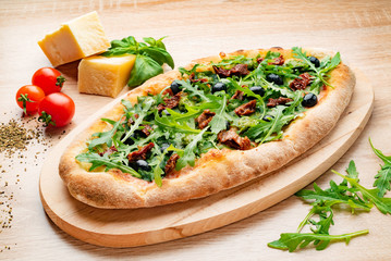 Pizza on Tabletop. Pizza wiht bacon, tomatoes, basil and arugula.