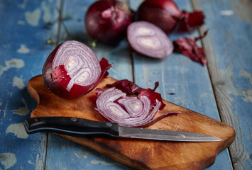 Red Onion Slices on wooden board with dark background 