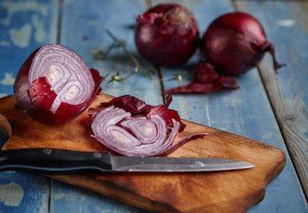 Red Onion Slices on wooden board with dark background 