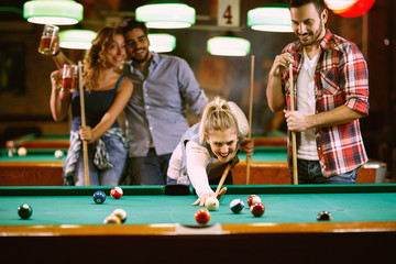 Friends playing billiard and enjoying in beer.
