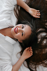 Naklejka premium Beautiful woman with long hair, red lips makeup in white shirt