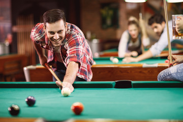 smiling man enjoying playing pool .