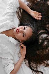 Naklejka premium Beautiful woman with long hair, red lips makeup in white shirt