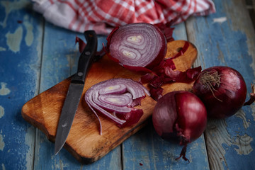 Red Onion Slices on wooden board with dark background 